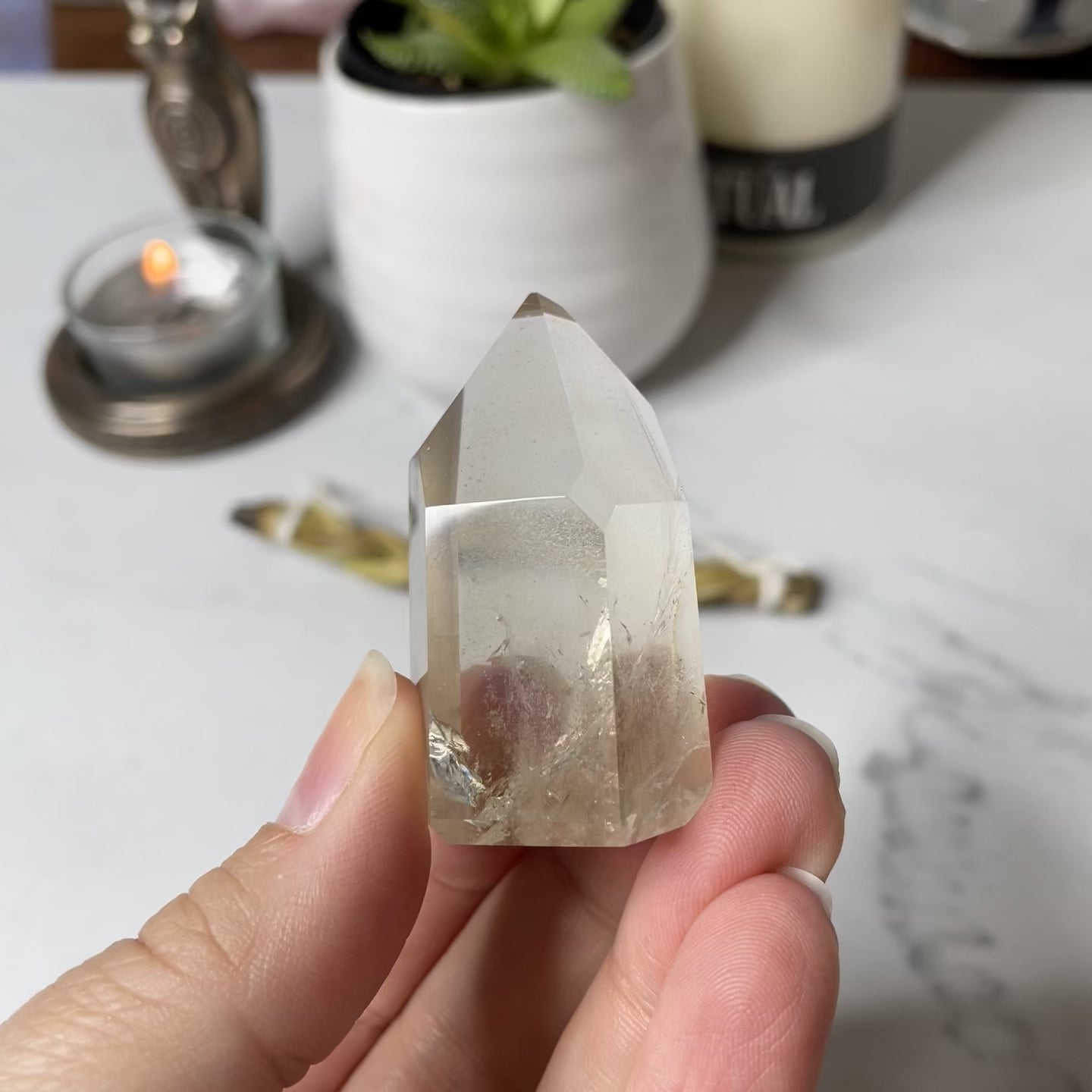Freya's Haven | Metaphysical & Crystal shop | A close up video of a Citrine Phantom tower held in a woman's hand with candles in the background.