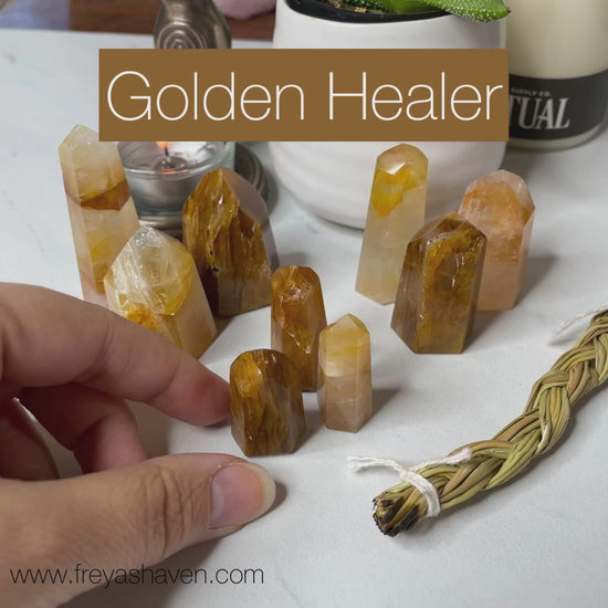 Freya's Haven | Metaphysical & Crystal shop | A close up video of a group of nine Golden Healer towers held in a woman's hand with candles in the background.