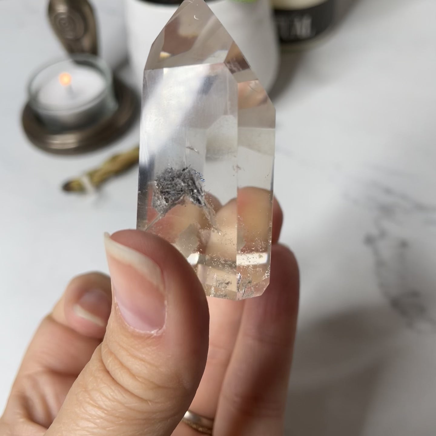 Freya's Haven | Metaphysical & Crystal shop | A close up video of a Lodalite  crystal held in a woman's hand with candles in the background.