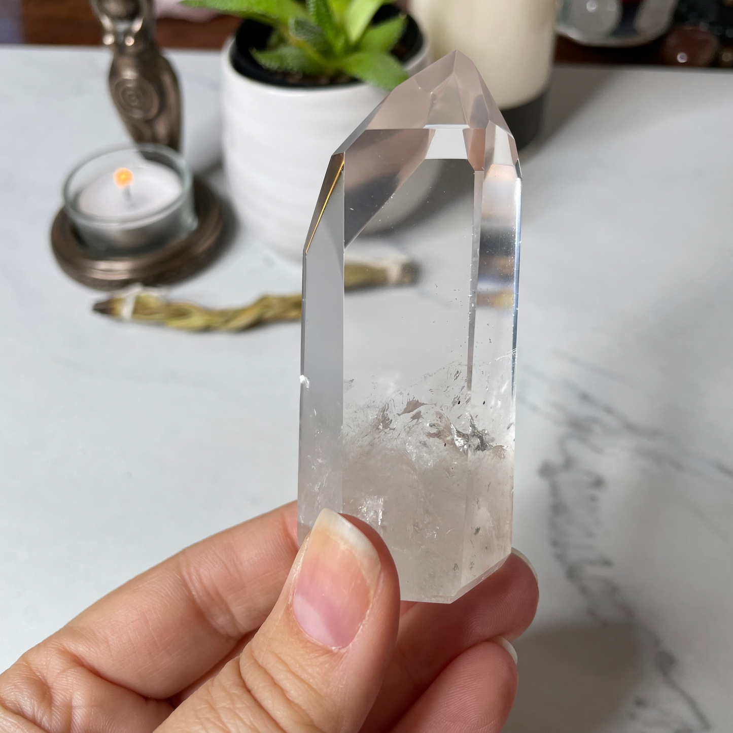 Freya's Haven | Metaphysical & Crystal shop | A close up photo of  a Lemurian seed crystal held in a woman's hand with candles in the background.