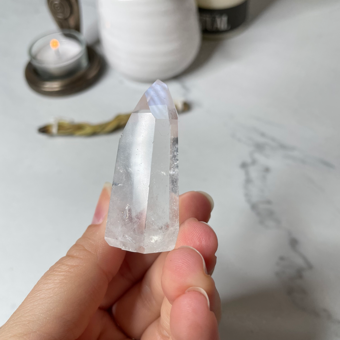 Freya's Haven | Metaphysical & Crystal shop | A close up photo of  a Lemurian seed crystal held in a woman's hand with candles in the background.