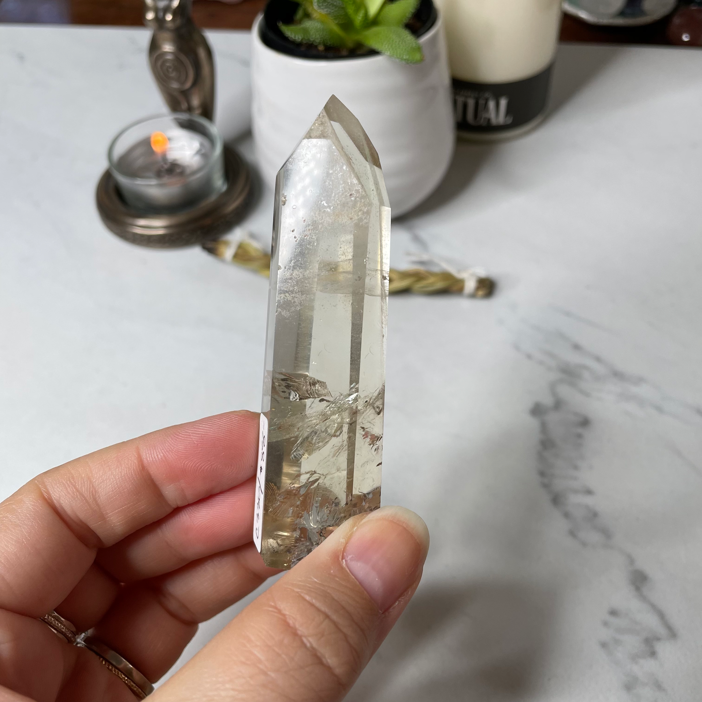 Freya's Haven | Metaphysical & Crystal shop | A close up photo of a Citrine Phantom tower held in a woman's hand with candles in the background.