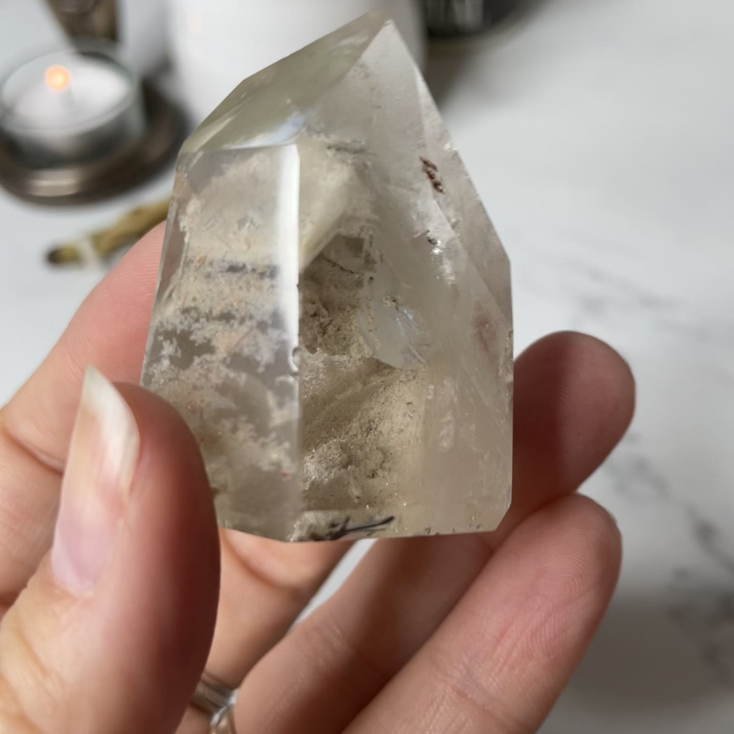 Freya's Haven | Metaphysical & Crystal shop | A close up video of a Lodalite  crystal held in a woman's hand with candles in the background.
