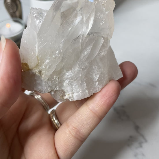 Freya's Haven | Metaphysical & Crystal shop | A close up video of a Clear Quartz Cluster held in a woman's hand with candles in the background.