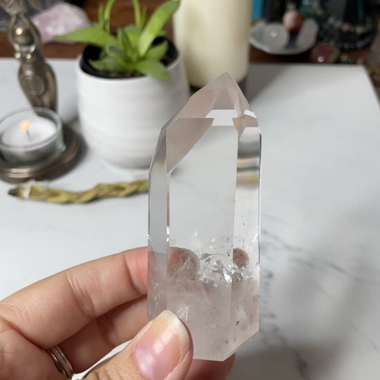 Freya's Haven | Metaphysical & Crystal shop | A close up video of a Lemurian seed crystal held in a woman's hand with candles in the background.