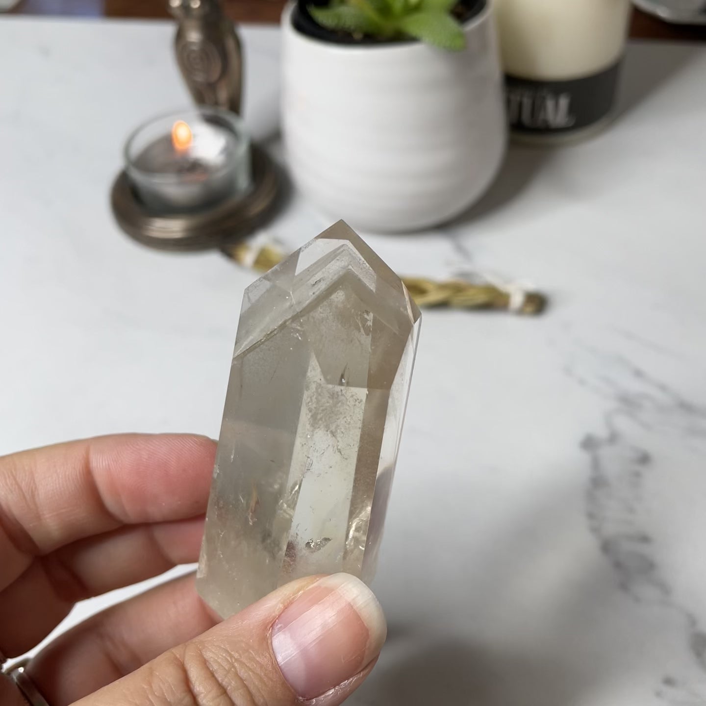 Freya's Haven | Metaphysical & Crystal shop | A close up video of a Citrine Phantom tower held in a woman's hand with candles in the background.