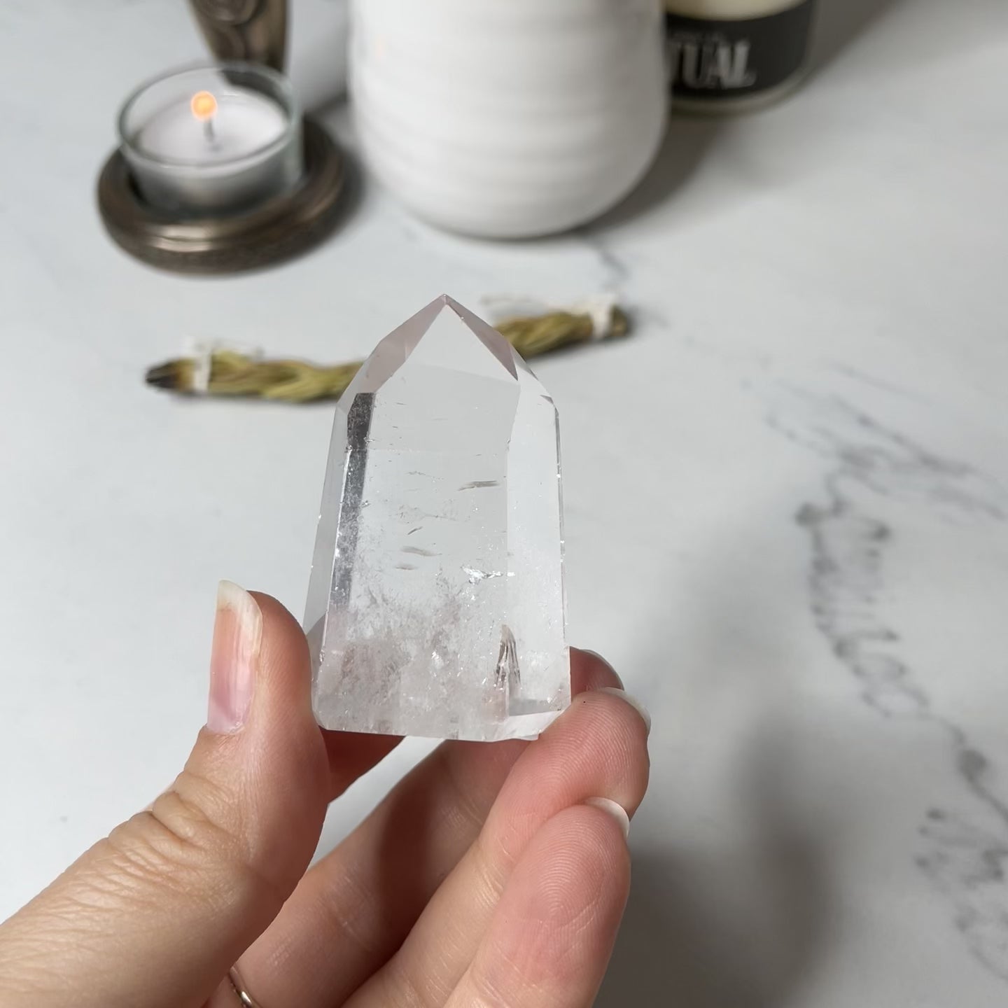 Freya's Haven | Metaphysical & Crystal shop | A close up video of  a Lemurian seed crystal held in a woman's hand with candles in the background.
